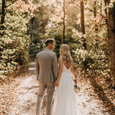 Hochzeitsfotoshooting, Brautpaar mit Blick in den Wald mit Rückenansicht