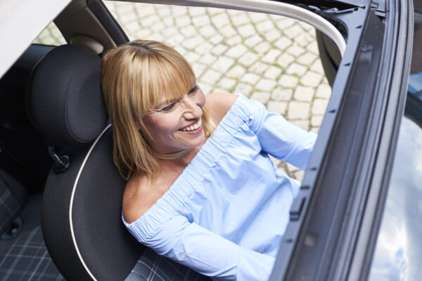 Frau sitzt im Cabrio und lacht vor sich hin