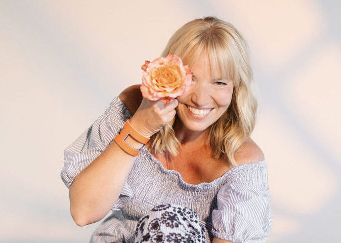 Sängerin mit einzelner orangefarbener Rose vor dem Auge im Blau weißen Kleid